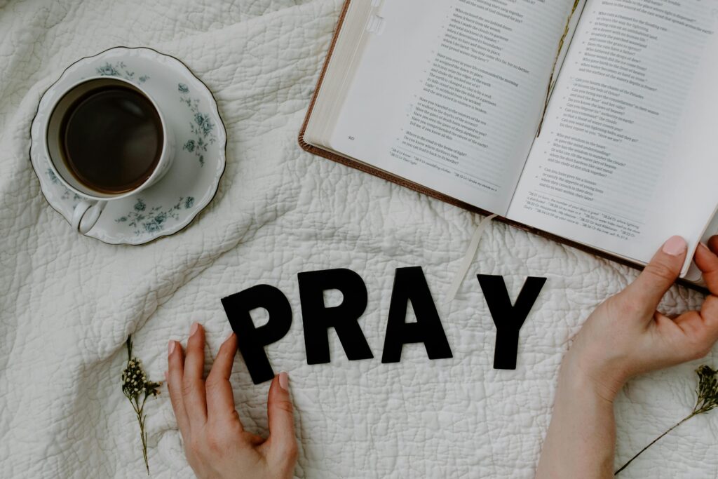 A bible with a pray word and coffee beside.